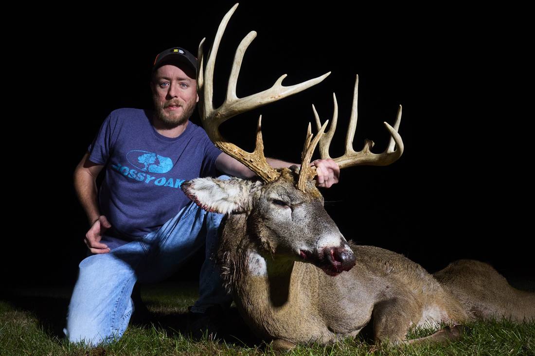 Hunter with a heavy-horned whitetail buck at night